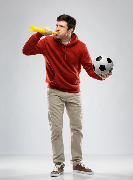 football fan with soccer ball blowing horn