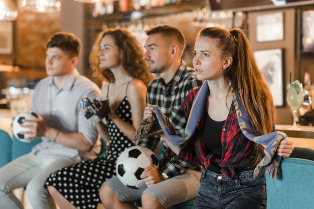 Football fans in bar watching soccer match on tv