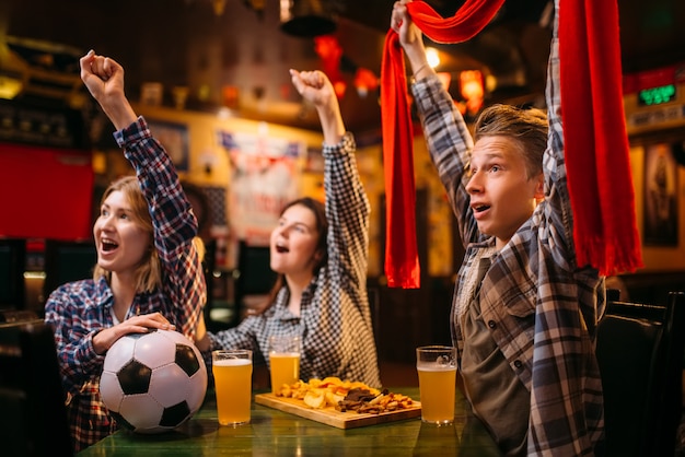 Football fans raise their hands up in sports bar