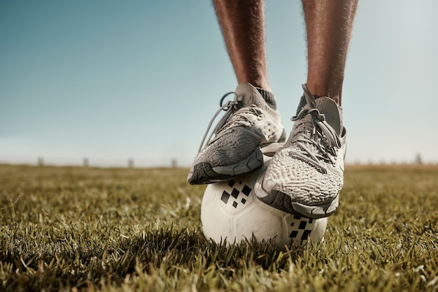 Football feet and balance on a soccer ball outdoor in nature on grass ready for exercise Fitness training and sport workout balancing for sports cardio and healthy athlete practice in the summer