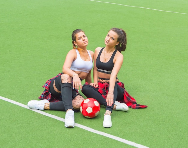 On the football field, two beautiful girls with the ball.