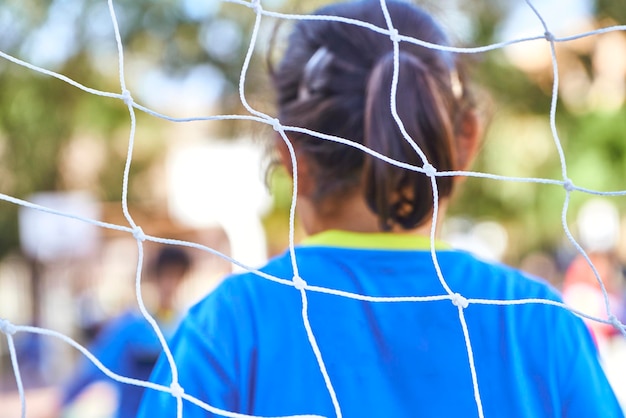 Сетка футбольных ворот на детском футбольном матче с неузнаваемой девушкой-вратарем на заднем плане