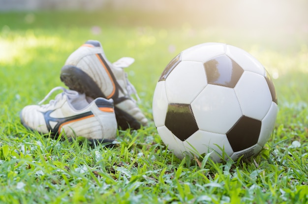 football on green grass and stud shoe with sun light