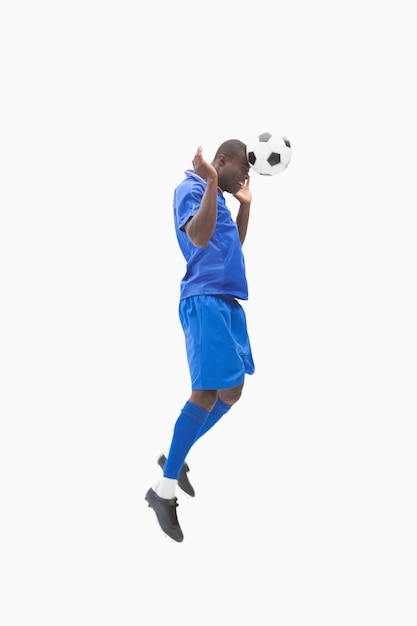 Photo football player in blue heading the ball