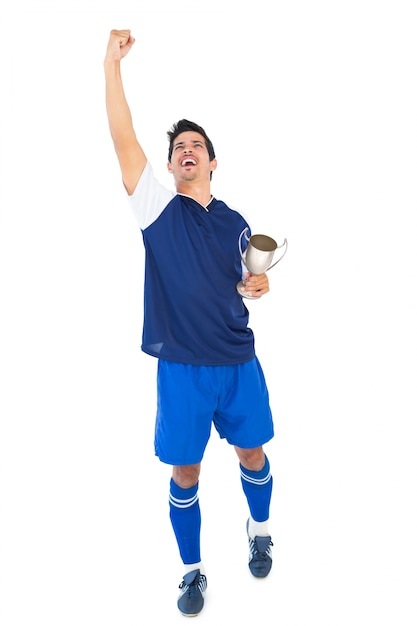 Football player in blue holding winners cup 