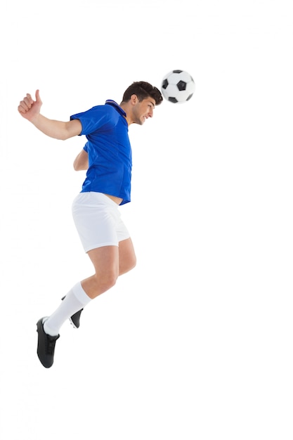 Football player in blue jersey heading ball on white background