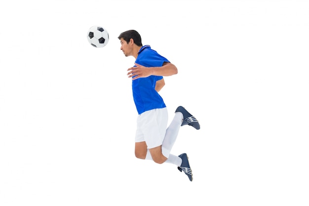 football player in blue jumping to ball