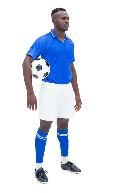 Football player in blue standing with the ball