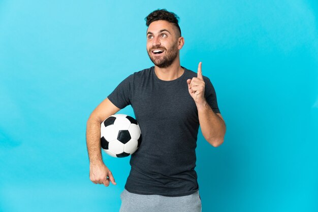 Football player isolated on blue background thinking an idea pointing the finger up