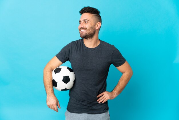 Football player isolated on blue posing with arms at hip and smiling