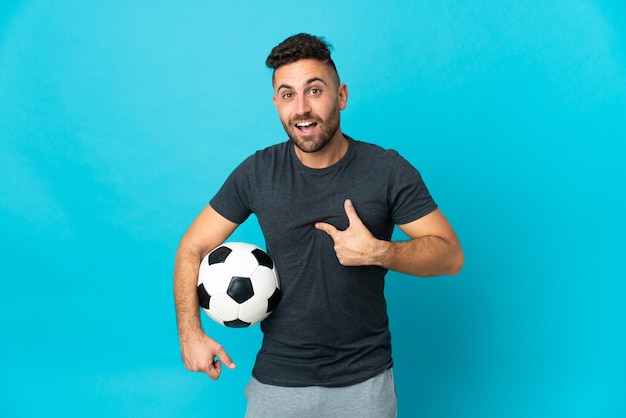 Football player isolated on blue wall with surprise facial expression