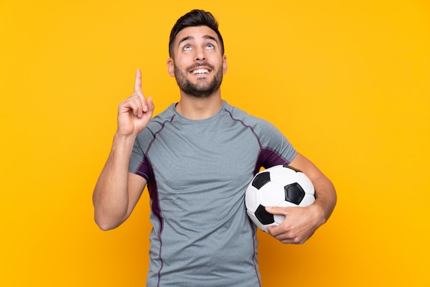 Football player man over isolated wall pointing up a great idea