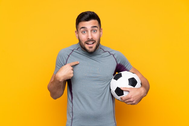 Football player man over isolated wall with surprise facial expression