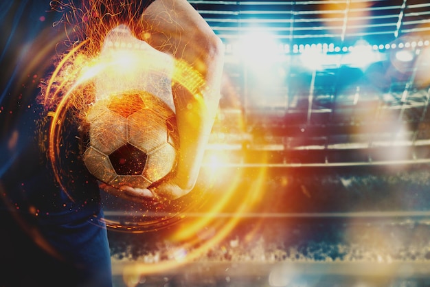 Football player ready to play with soccerball in flame at the stadium