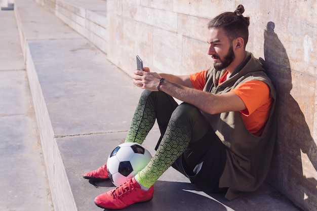 Football player rest consulting his mobile phone