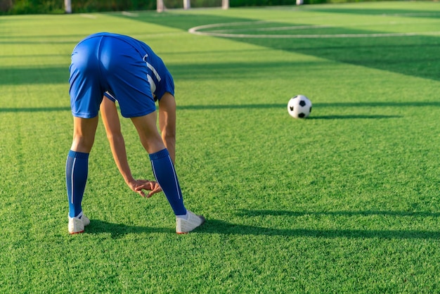 Футболист разминается перед ударом со штрафного или ударом, чтобы выиграть счет на травяном стадионе