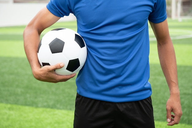 サッカー選手、黒のサッカーボールを持って、青いシャツを着て。