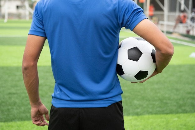 축구 선수는 파란색 셔츠를 입고 검은 축구 공을 들고.