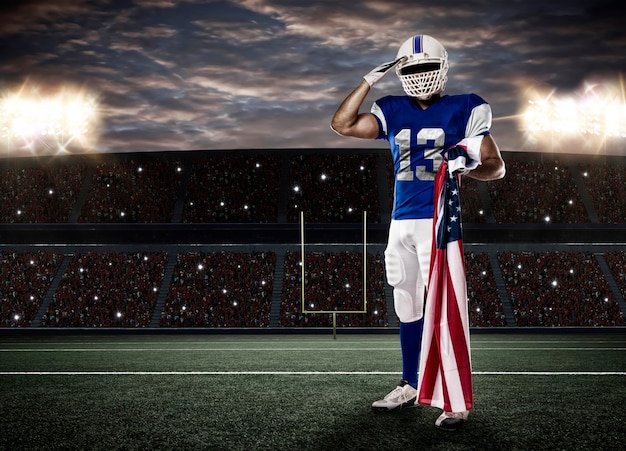Фото Футболист в синей форме салютует американским флагом на стадионе