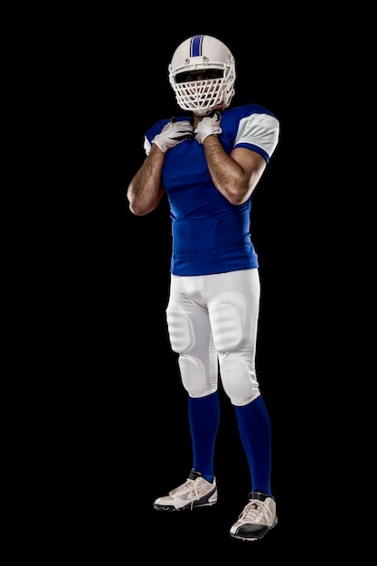 Foto giocatore di football americano con un'uniforme blu su una parete nera