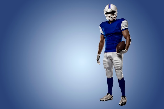 Football Player with a blue uniform on a blue wall