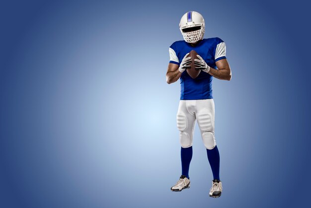 Football Player with a blue uniform on a blue wall