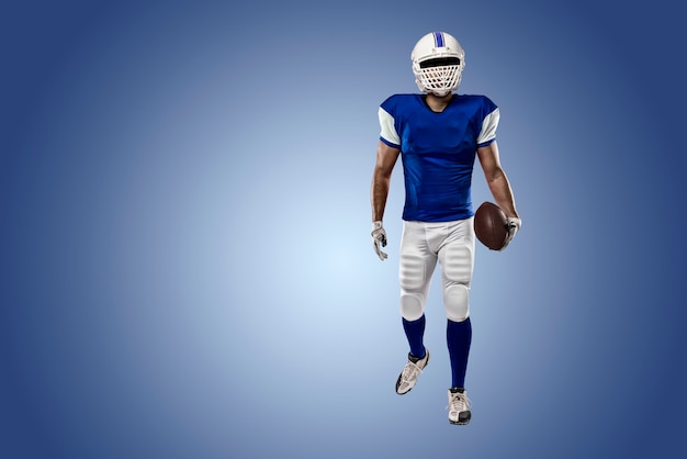 Football Player with a blue uniform on a blue wall