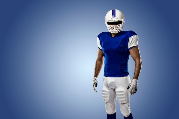 Foto giocatore di football americano con un'uniforme blu su una parete blu