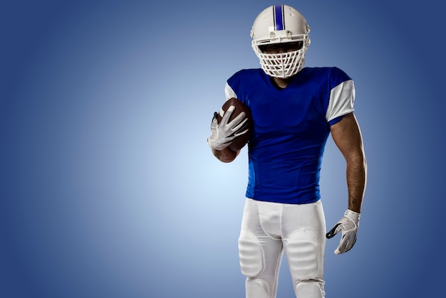 Football Player with a blue uniform on a blue wall