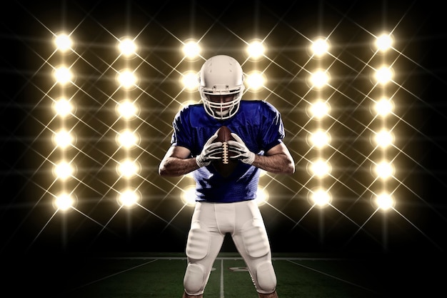Photo football player with a blue uniform in front of lights