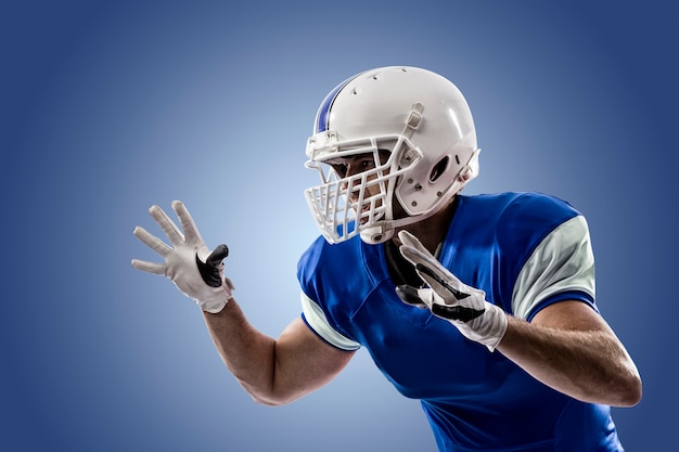 Football Player with a blue uniform making a tackle on a blue wall