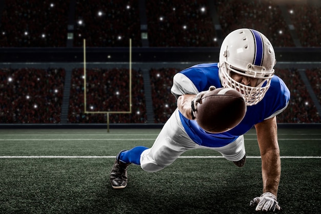 Football Player with a blue uniform scoring on a Stadium