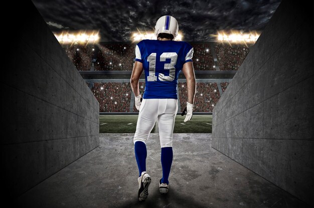 Giocatore di football americano con un'uniforme blu che cammina da un tunnel dello stadio