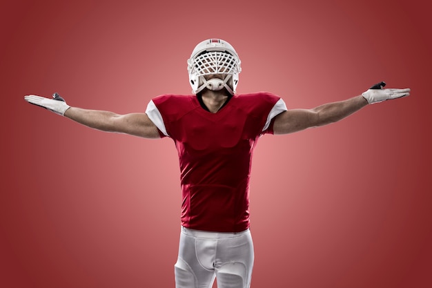 Football Player with a red uniform celebrating, on a red wall