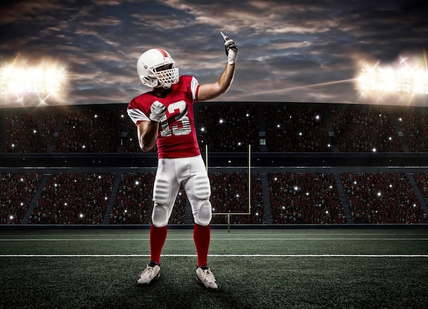 Giocatore di football americano con una divisa rossa che fa un selfie su uno stadio.