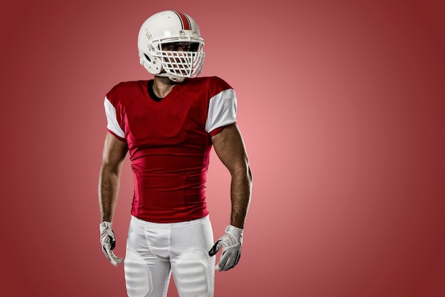 Photo football player with a red uniform on a red wall