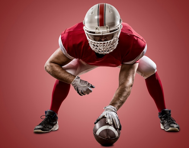 Football Player with a red uniform on the scrimmage line, on a red wall