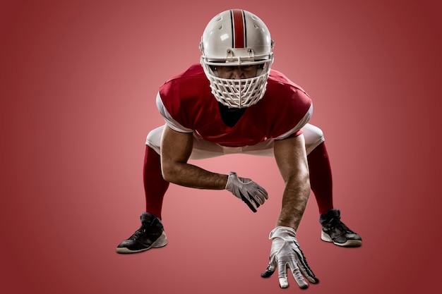 Football Player with a red uniform on the scrimmage line on a red wall