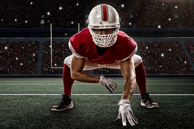 Football Player with a red uniform on the scrimmage line, on a Stadium.