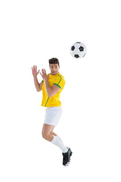Football player in yellow jersey jumping to ball