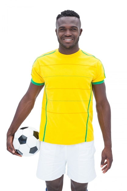 Football player in yellow standing with the ball on white background