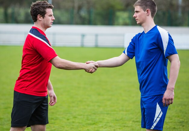 Football players in blue and red shaking hands