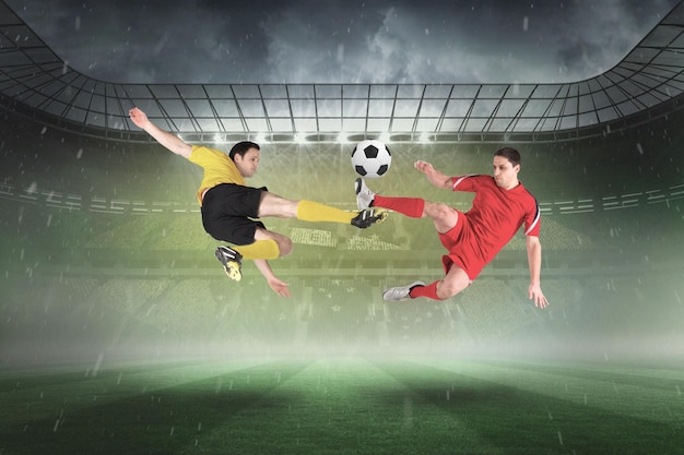 Photo football players tackling for the ball against misty football stadium under spotlights