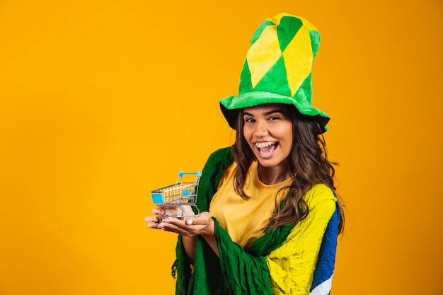 Football promotion. Woman holding a mini shopping cart in hands wearing brazilian clothes.