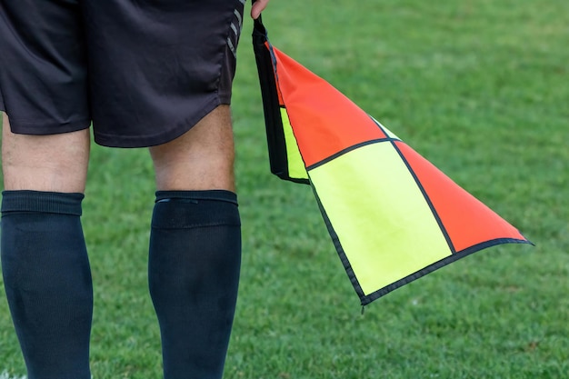 Football soccer arbiter assistant with flag at hands Blurred green field background close up