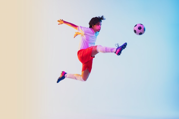 Giocatore di calcio o di calcio su gradiente alla luce al neon - movimento, azione, concetto di attività