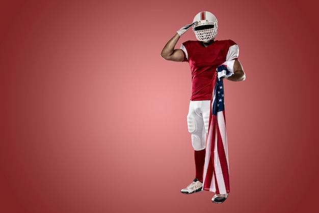Football-speler met een rood uniform die met een Amerikaanse vlag, op een rode muur
