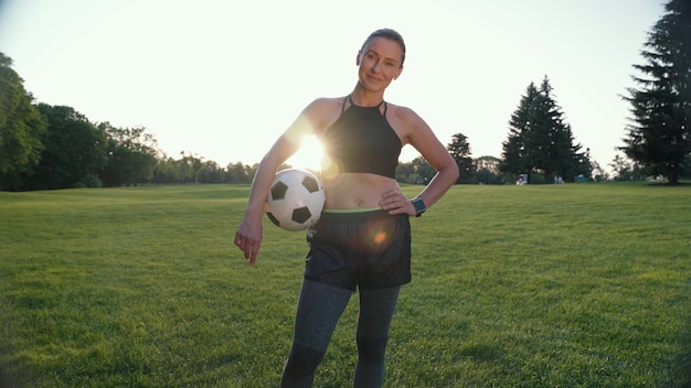 Foto football speler portret van mooie en sportieve vrouw met voetbal in de hand kijken naar