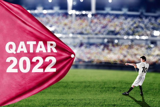 写真 サッカー選手はカタール 2022 のテキストで布を引っ張る