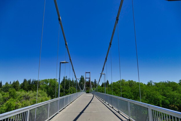 Footbridge against clear blue sky